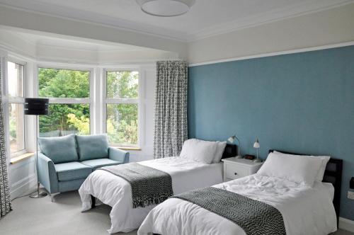 a bedroom with two beds and a blue wall at Cranford Holiday House in Crieff