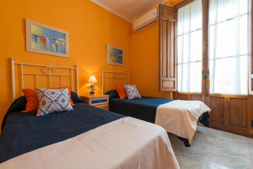 グラナダにあるFlor De Lisのオレンジ色の壁の客室内のベッド2台