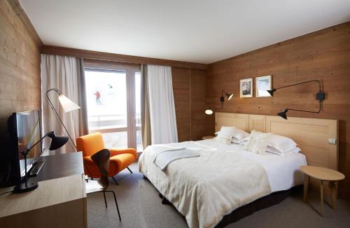 a hotel room with a bed and a television at Les Trois Vallées, a Beaumier hotel in Courchevel