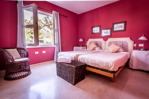 a bedroom with pink walls and a bed and a chair at Villa Bella Lanzarote in Costa Teguise