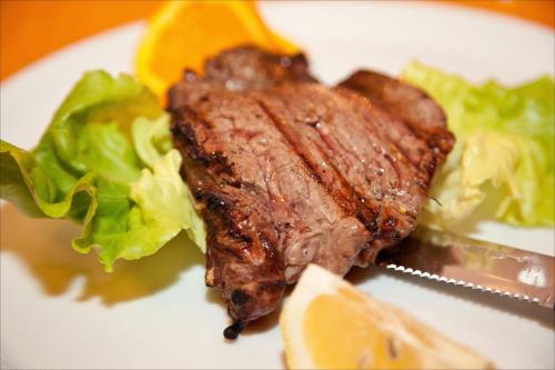 a piece of steak and lettuce on a white plate at Le Vecchie Cantine in Chianni