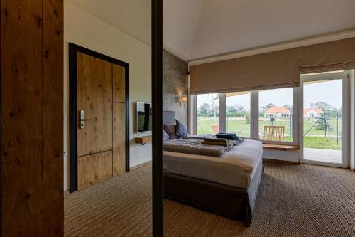 a bedroom with a bed and a large window at Chalets Franciska Major, Pro Village in Sopronkövesd