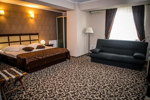 a bedroom with a bed and a couch and a chair at Hotel Megalos in Constanţa