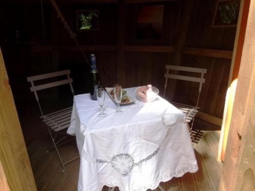 a white table with a bottle of wine and two chairs at Les cabanes du lac du Der in Giffaumont