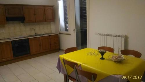 een gele tafel in een keuken met een gele tafelkleed bij B&B Madau in Samughèo