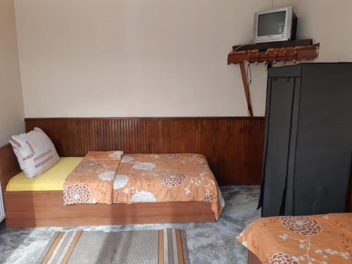 a bedroom with two beds and a tv on the wall at byala kısta apart in Isperikh