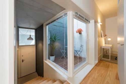Cette chambre dispose d'une grande fenêtre avec une plante. dans l'établissement BmyGuest - Villa Lóios Terrace Apartment, à Porto