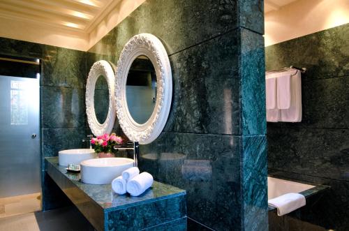 a bathroom with two sinks and a tub and mirrors at Tigmiza Boutique Hotel & Spa in Marrakech