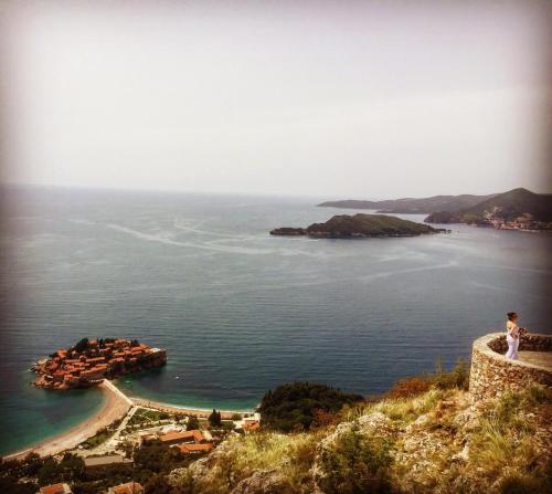 a man standing on top of a hill looking at the ocean at Apartments Sveti Stefan MNE in Sveti Stefan
