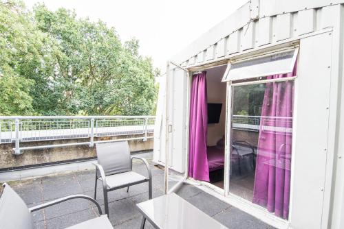 a balcony with pink curtains and a table and chair at Safestay London Kensington Holland Park in London