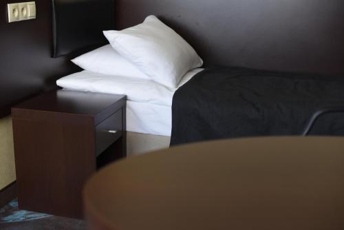 a room with a bed with a pillow and a table at Hotel Portofino in Włocławek
