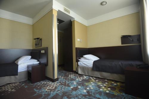 a hotel room with two beds and a doorway at Hotel Portofino in Włocławek