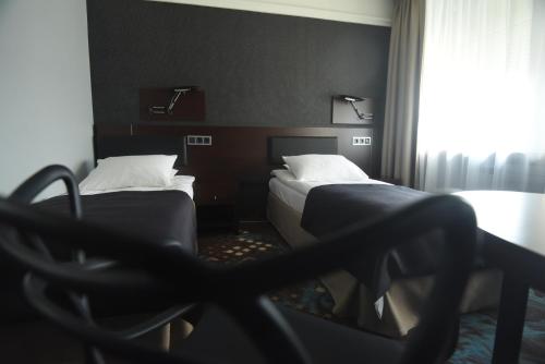 a hotel room with two beds and a chair at Hotel Portofino in Włocławek