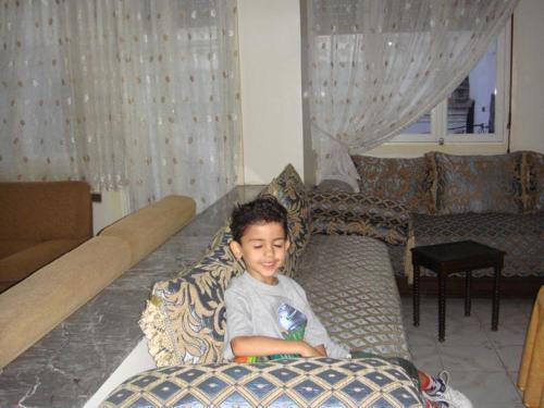 a young boy sitting on a couch in a living room at Appartement Familial Emile Zola in Casablanca