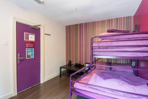 a room with purple bunk beds and a purple door at Safestay London Kensington Holland Park in London