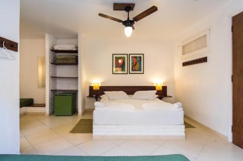 a bedroom with a white bed and a ceiling fan at Pousada Recanto das Palmeiras in Ubatuba