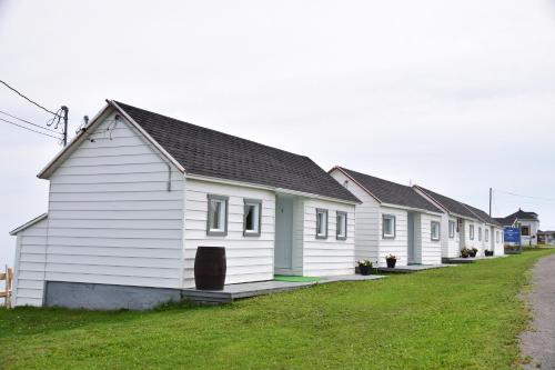 una fila de casas blancas al lado de una carretera en Les Cabines sur Mer, en Cap-des-Rosiers