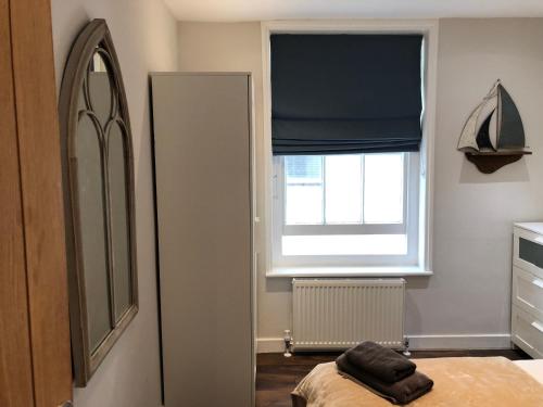1 dormitorio con espejo y ventana en Modern One Bedroom Apartment near the seafront, en Portsmouth