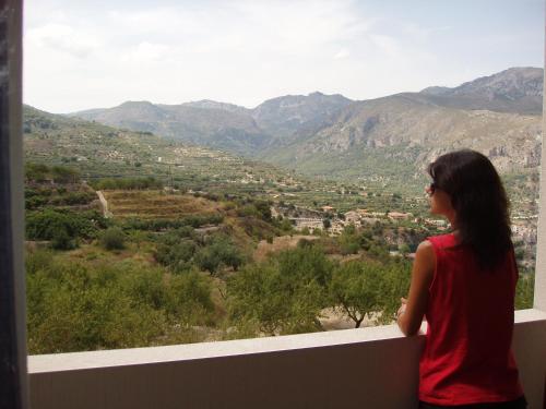a woman standing on a balcony looking out at a valley at APARTAMENTOS SERRELLA - Rural Guadalest in Benimantell