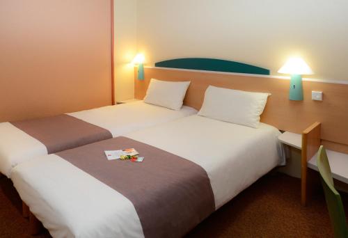 two beds in a hotel room with two lamps at ibis Charleroi Centre Gare in Charleroi