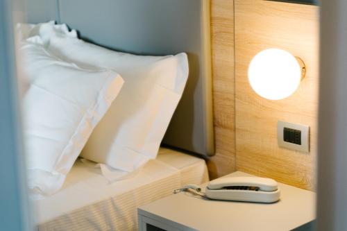 a hotel room with a bed with pillows and a phone at Bike&Boat Argentario Hotel in Porto Santo Stefano