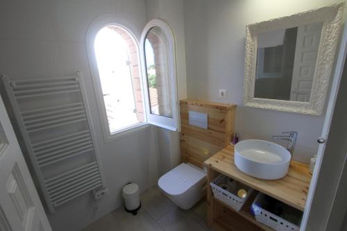 a bathroom with a sink and a toilet and a mirror at Casa Acacia Mar in Cambrils