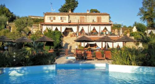 a villa with a swimming pool in front of a house at La Valle Del Sole Country House in SantʼIppolito
