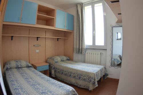 ein kleines Zimmer mit 2 Betten und einem Fenster in der Unterkunft Residence Villa Miky in Albenga