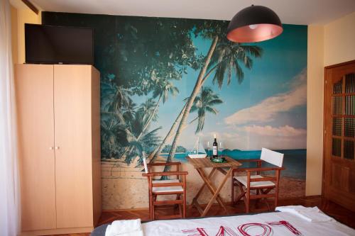 a bedroom with a mural of palm trees and a table at Apartmani La Sa in Osijek