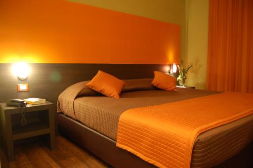 a bedroom with a bed with an orange wall at Andrea Doria Hotel in Marina di Ragusa
