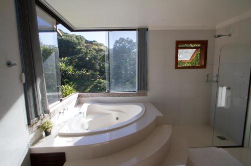 uma casa de banho branca com uma banheira e uma janela em Canto Da Mole em Florianópolis