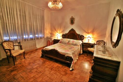 1 dormitorio con cama, espejo y silla en Casa Añon, en Cabana de Bergantiños