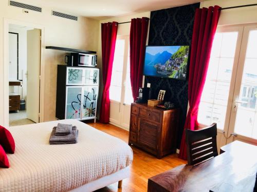 a bedroom with a bed and a tv and red curtains at Villa Florian in Neuilly-Plaisance