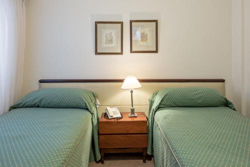 a hotel room with two beds and a phone on a table at Hotel Presidente in Mar del Plata