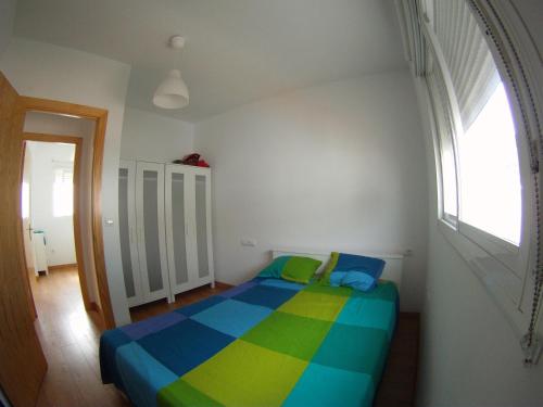 - une chambre avec un lit coloré et une fenêtre dans l'établissement Tarifa Surf Center Apartment, à Tarifa
