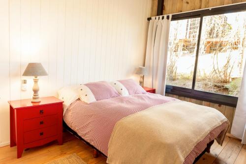 a bedroom with a bed with a red dresser and a window at Zulu Beach in José Ignacio