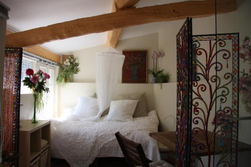 - une chambre dotée d'un lit avec des draps blancs et des fleurs dans l'établissement la maison bleue, à Carros