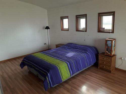 a bedroom with a bed and a dresser and windows at Lemuria Hostel in Valparaíso