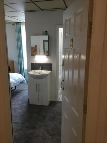 a bathroom with a sink and a mirror and a bed at The Danescourt in Blackpool