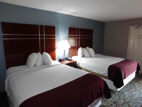 a hotel room with two beds and a lamp at Days Inn by Wyndham West Des Moines - Clive in Clive