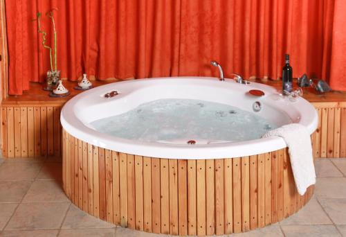 a hot tub in a room with a red curtain at Between Water and Sky in Neot Golan