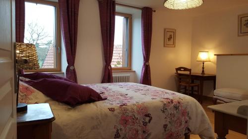a bedroom with a bed and two windows at Le BOCAGE in Sartilly