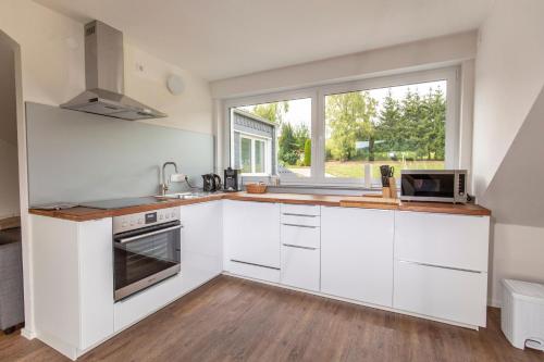 a kitchen with white cabinets and a window at Ferienwohnungen "Am Mühlenberg" in Lindlar
