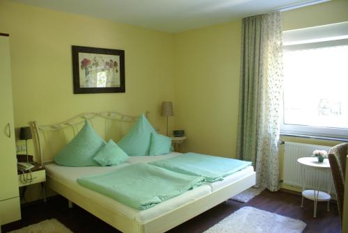 a bedroom with a bed with blue pillows and a window at Hotel Storchen in Rheinfelden