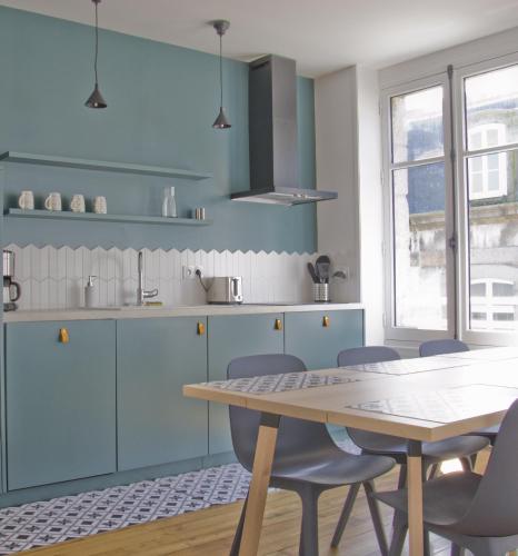 une cuisine avec des armoires bleues et une table et des chaises dans l'établissement Appartement de charme, à Saint-Malo