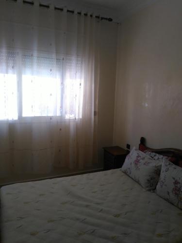 a bedroom with a bed and a window with curtains at Al Oualidia Dar Diafa in Oualidia