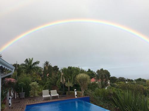 a rainbow in the sky over a swimming pool at Villa Cajou chambres d'hôtes chez l'habitant et Zanzibar cottage in Trois-Rivières