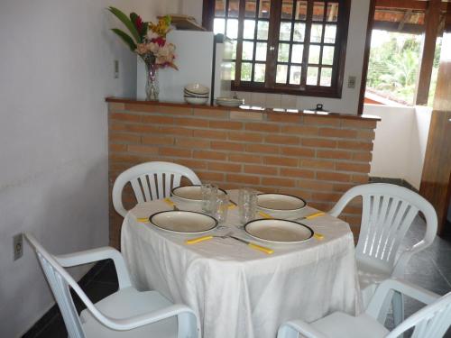 une table avec un chiffon de table blanc et des chaises blanches dans l'établissement Chalés Santorini, à Caraguatatuba