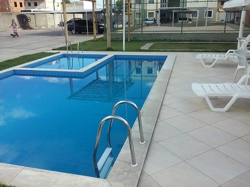a blue swimming pool with two white chairs next to it at Apartamento mobiliado in Feira de Santana