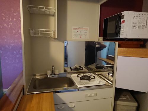 a small kitchen with a sink and a microwave at Big Tree JUDO ハウス in Urasoe